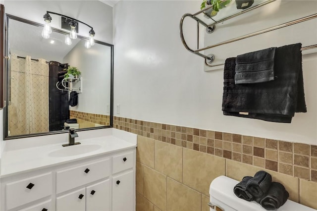 bathroom featuring vanity, toilet, and tile walls