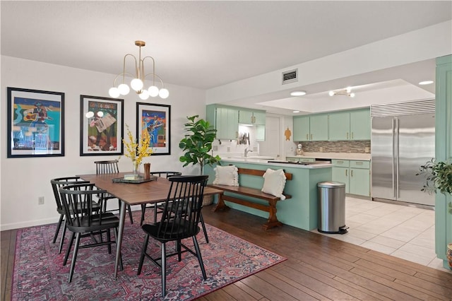 dining space with light wood-type flooring, sink, and an inviting chandelier