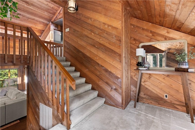 stairway featuring lofted ceiling, wood walls, and wood ceiling