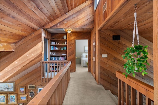 hallway featuring wood ceiling, wood walls, light colored carpet, and lofted ceiling