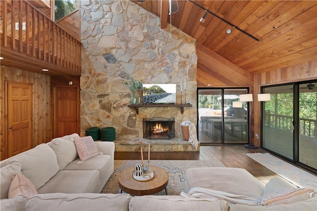 living room with rail lighting, a stone fireplace, high vaulted ceiling, wood ceiling, and hardwood / wood-style flooring