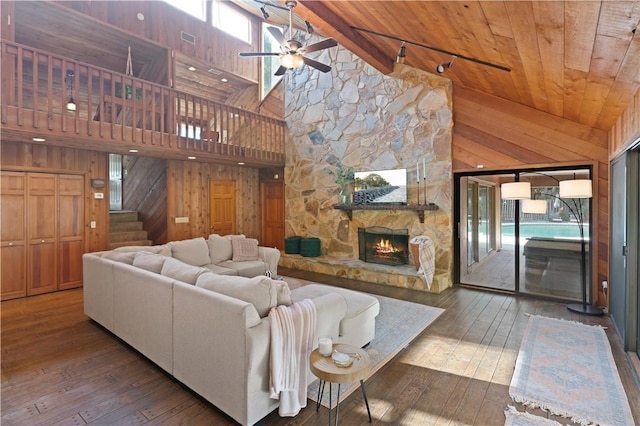 living room featuring wooden walls, wood-type flooring, and high vaulted ceiling