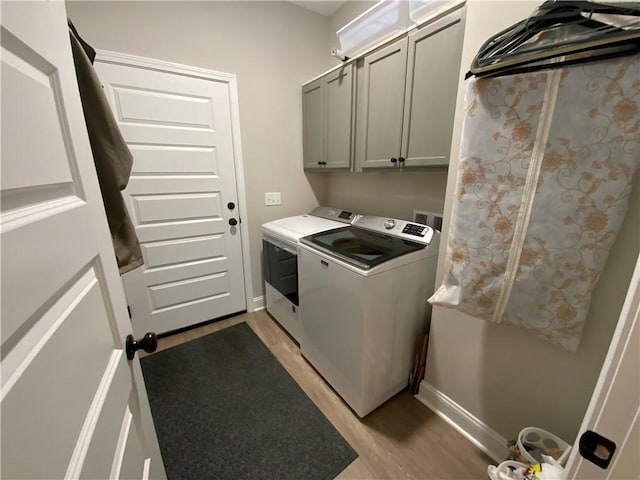 laundry area featuring cabinets, light hardwood / wood-style floors, and washer and dryer