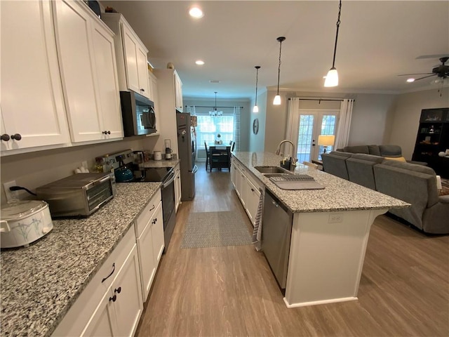 kitchen with stainless steel appliances, a center island with sink, white cabinets, and decorative light fixtures