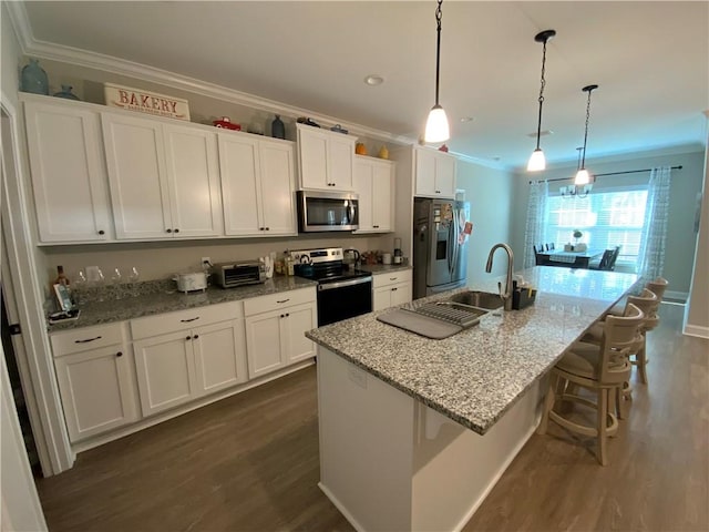 kitchen featuring stainless steel appliances, decorative light fixtures, a kitchen island with sink, and white cabinets