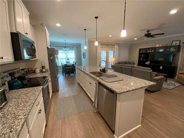 kitchen featuring pendant lighting, stainless steel appliances, a center island with sink, and white cabinets