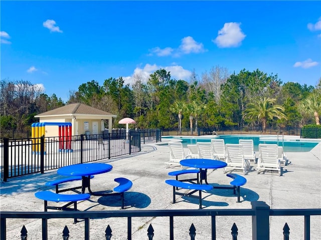 view of play area featuring a community pool and a patio