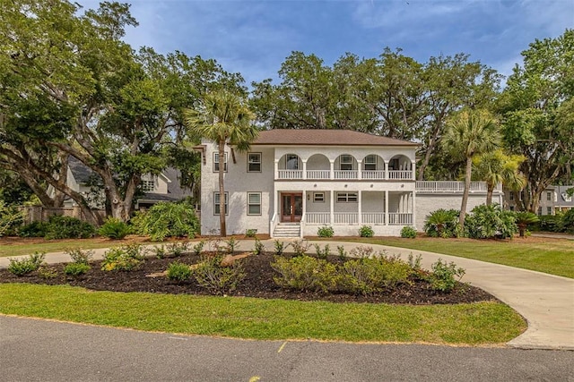 view of front facade featuring a balcony, driveway, a porch, and stucco siding