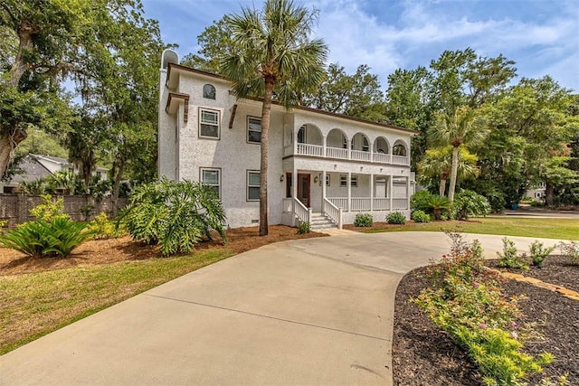 mediterranean / spanish-style house with a balcony, a front yard, a porch, and stucco siding