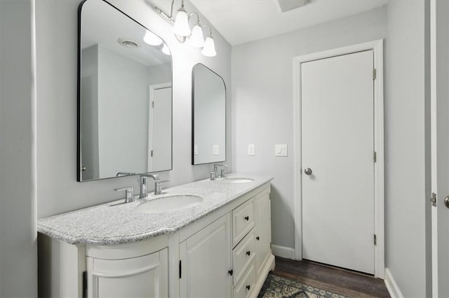 full bath featuring wood finished floors, a sink, baseboards, and double vanity