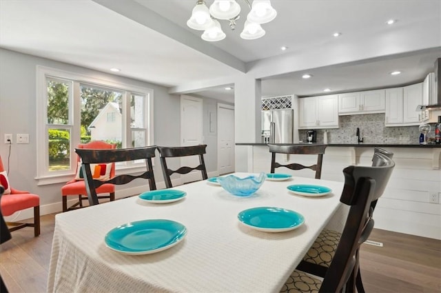 dining room featuring recessed lighting, baseboards, light wood finished floors, and an inviting chandelier