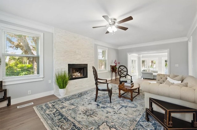 living area with crown molding, dark wood finished floors, visible vents, and a fireplace