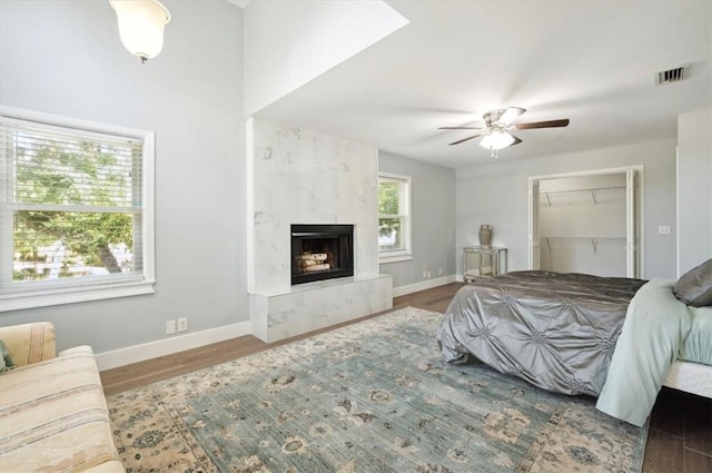 bedroom featuring visible vents, dark wood-style flooring, a high end fireplace, and baseboards