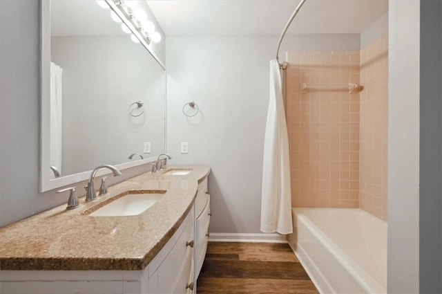 full bathroom with double vanity, wood finished floors, a sink, and shower / bath combo with shower curtain