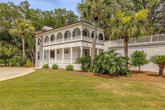 mediterranean / spanish-style house with a balcony, a front lawn, and stucco siding