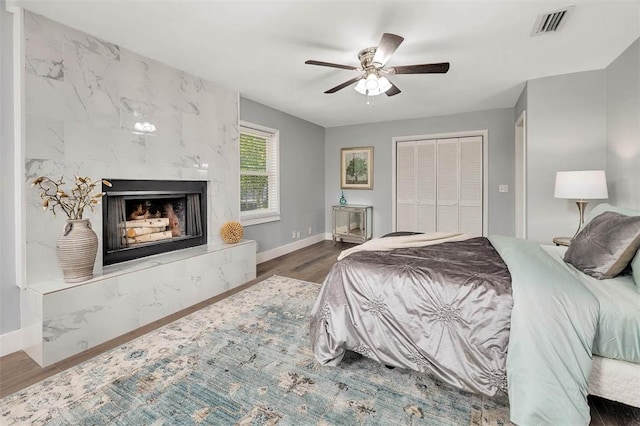 bedroom featuring baseboards, visible vents, dark wood-type flooring, a closet, and a high end fireplace