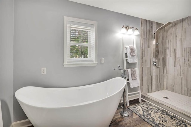 bathroom with a freestanding bath, a shower stall, baseboards, and wood finished floors