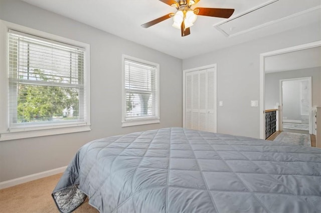 carpeted bedroom with a ceiling fan, a closet, attic access, and baseboards