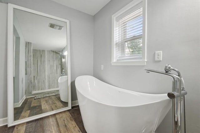 bathroom featuring a soaking tub, visible vents, and wood finished floors