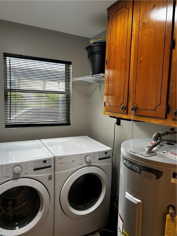 604 E Waring St, Waycross, GA 31501 - laundry area featuring electric water heater, cabinet space, and separate washer and dryer