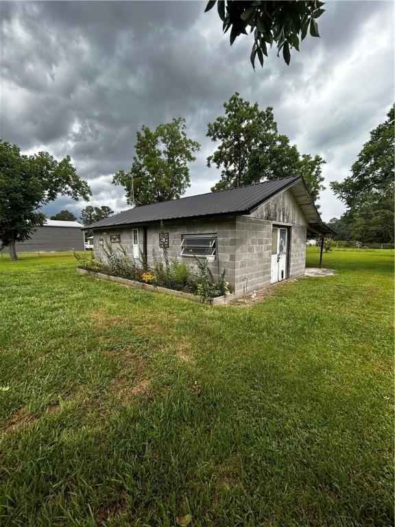 604 E Waring St, Waycross, GA 31501 - view of side of home featuring a lawn, concrete block siding, and a metal roof