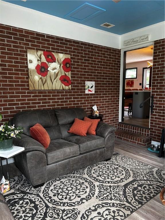 604 E Waring St, Waycross, GA 31501 - living area featuring wood finished floors, brick wall, and attic access