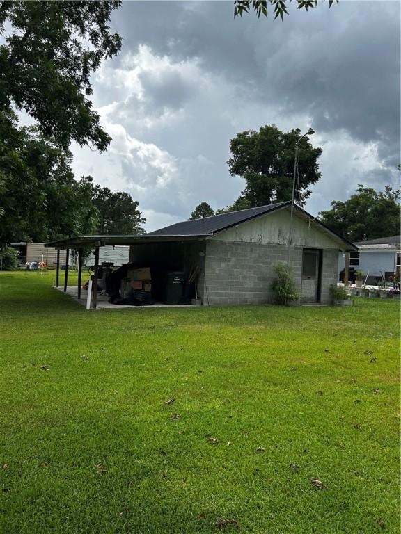 604 E Waring St, Waycross, GA 31501 - view of side of home with a yard, concrete block siding, and a carport