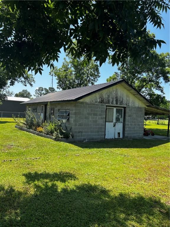 604 E Waring St, Waycross, GA 31501 - view of home's exterior featuring concrete block siding, a lawn, and a metal roof