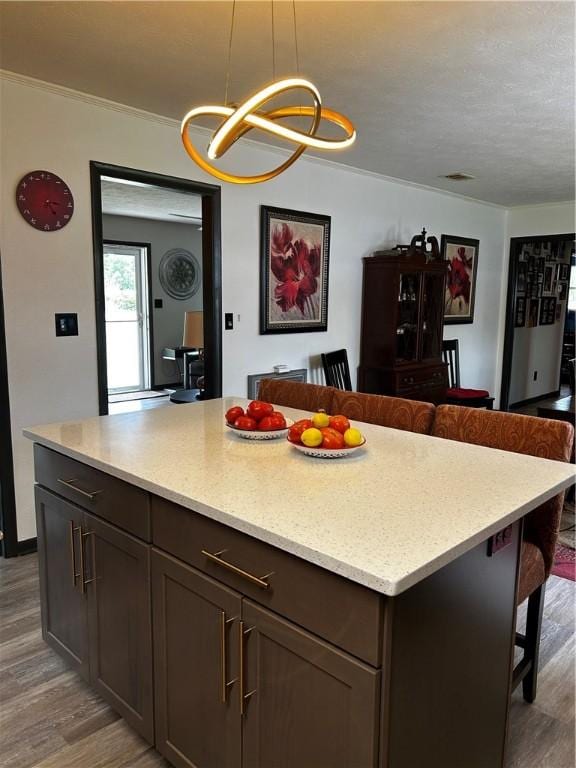 604 E Waring St, Waycross, GA 31501 - kitchen featuring a kitchen bar, wood finished floors, open floor plan, a chandelier, and crown molding