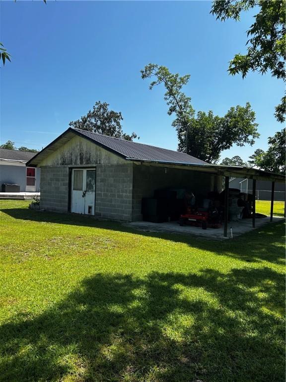 604 E Waring St, Waycross, GA 31501 - rear view of house featuring a lawn, concrete block siding, an attached carport, and a metal roof