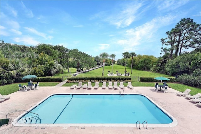 view of pool with a patio area and a yard