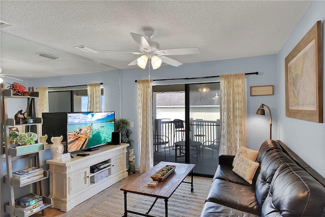 living room featuring a textured ceiling, light hardwood / wood-style floors, and ceiling fan