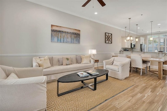 living room with light wood-type flooring, ceiling fan, and crown molding