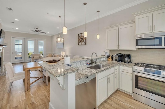 kitchen with kitchen peninsula, stainless steel appliances, white cabinets, and sink