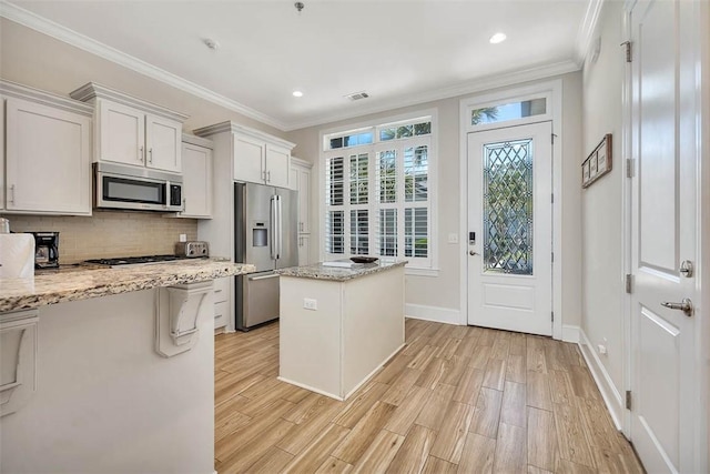 kitchen featuring light stone counters, stainless steel appliances, light hardwood / wood-style flooring, a center island, and white cabinetry