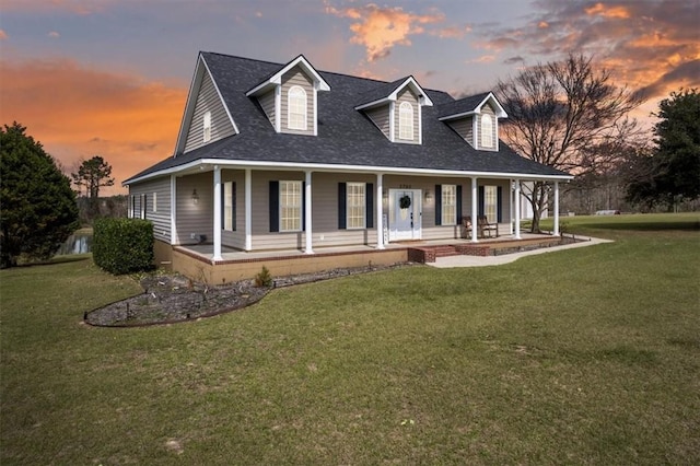 country-style home with covered porch, a front lawn, and roof with shingles