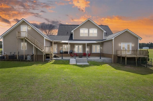 back of house at dusk featuring french doors, a lawn, stairway, a patio area, and cooling unit