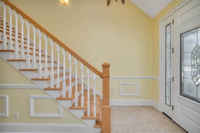 tiled foyer entrance featuring stairs, baseboards, and lofted ceiling