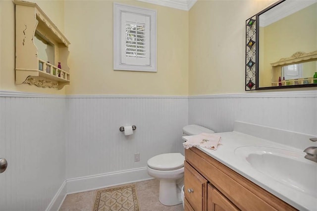 half bathroom with tile patterned flooring, wainscoting, vanity, baseboards, and toilet