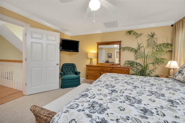 carpeted bedroom with visible vents, a ceiling fan, baseboards, and crown molding