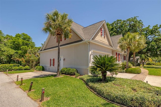 view of home's exterior with a garage, roof with shingles, stucco siding, concrete driveway, and a lawn