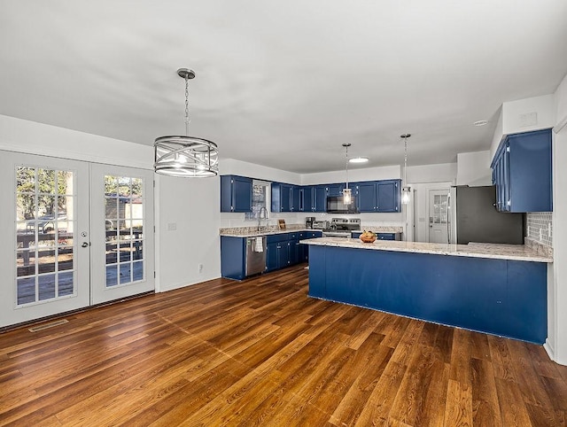 kitchen with sink, appliances with stainless steel finishes, dark hardwood / wood-style floors, blue cabinets, and kitchen peninsula