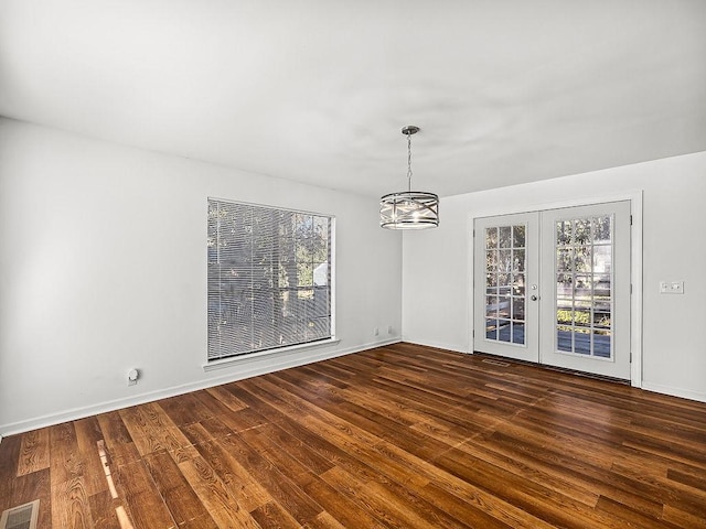 empty room with dark hardwood / wood-style flooring, a wealth of natural light, and french doors