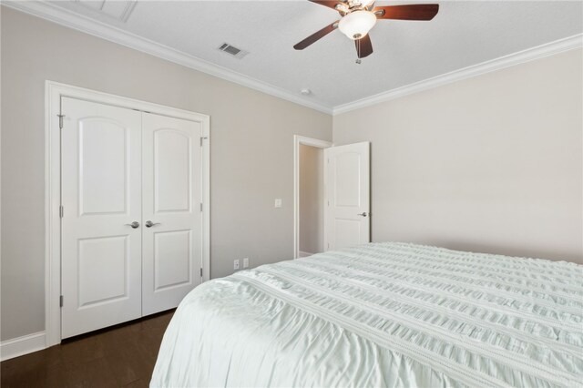 bedroom with crown molding, a closet, a ceiling fan, visible vents, and dark wood-type flooring