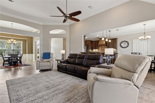living area with visible vents, wainscoting, ornamental molding, ceiling fan with notable chandelier, and light tile patterned floors