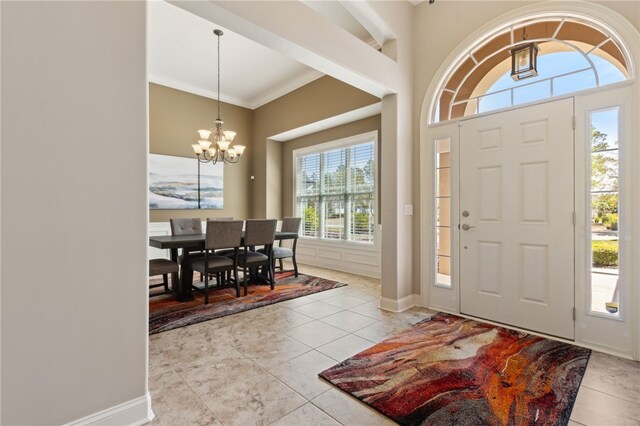 foyer with tile patterned floors, baseboards, ornamental molding, and a chandelier