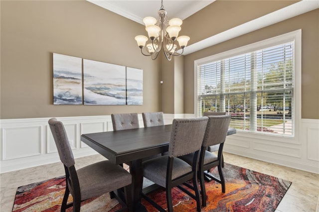 dining space featuring a decorative wall, an inviting chandelier, wainscoting, and ornamental molding