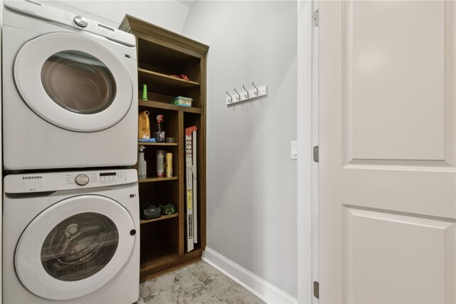 laundry room with baseboards, laundry area, and stacked washer / drying machine