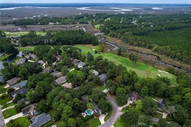 drone / aerial view with a view of trees, view of golf course, and a residential view