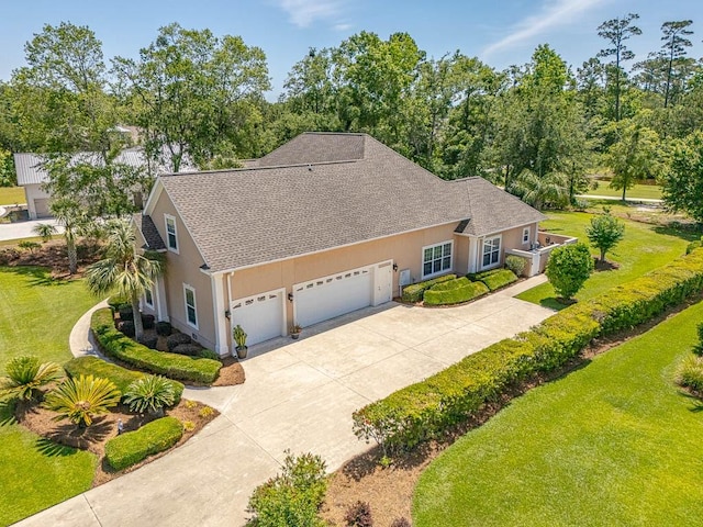 17 Willow Ct, Brunswick, GA 31523 - view of front of home with an attached garage, a shingled roof, driveway, a front lawn, and stucco siding